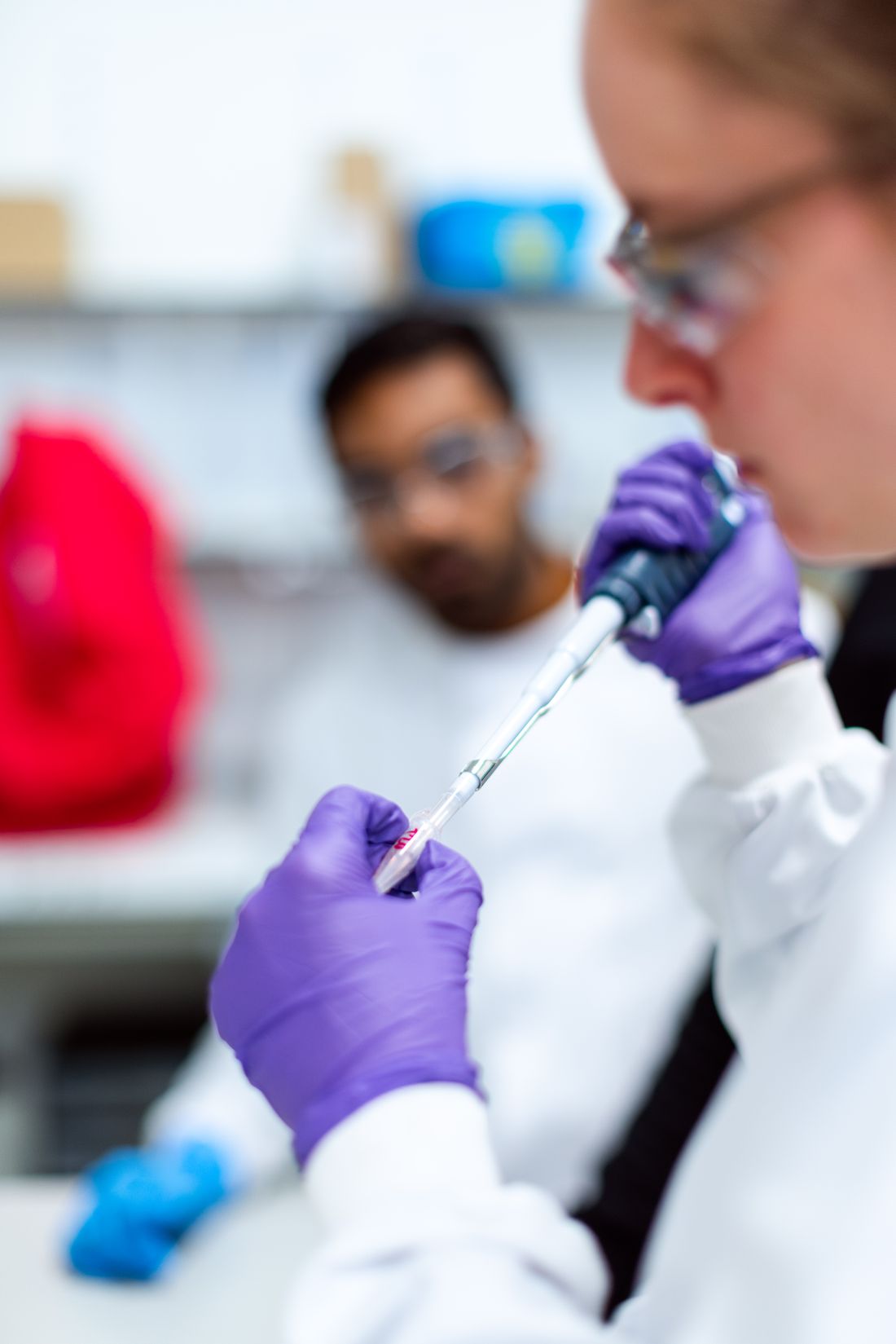 A young scientist in safety glasses pipetting a sample at the bench